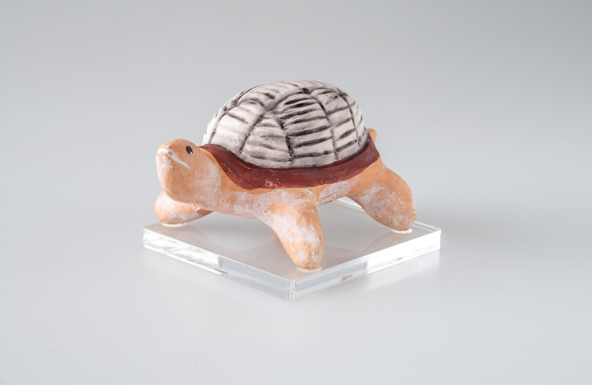 Ceramic turtle figurine on clear base.